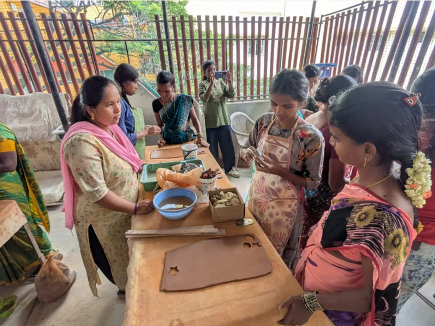 Women gathered around a worktable at the Headstreams Centre, trying clay tools and cut-out shapes for the first time