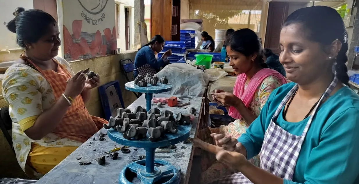 Women of the Aalamba Livelihood Collective hand-building small clay elephants at a shared worktable
