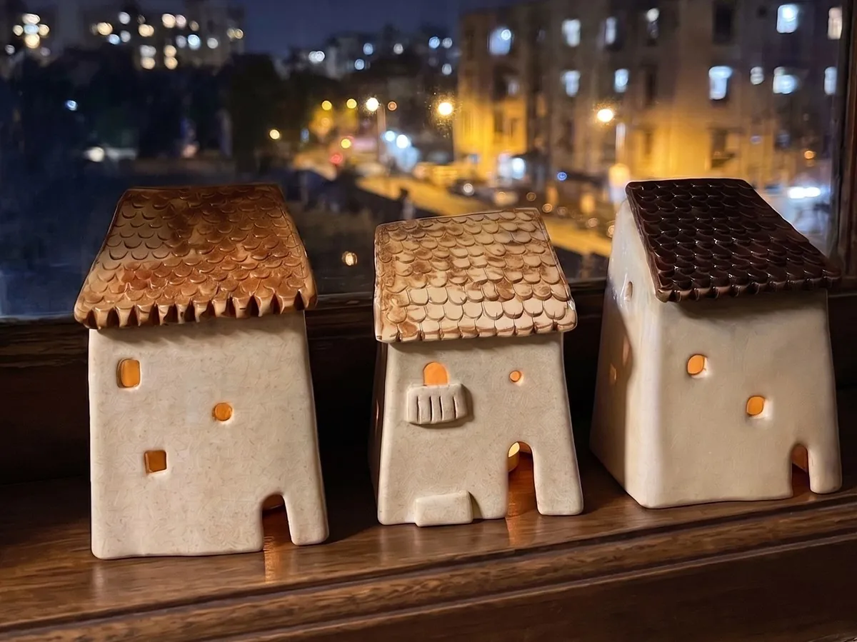 Small ceramic houses lit from within, arranged at a window