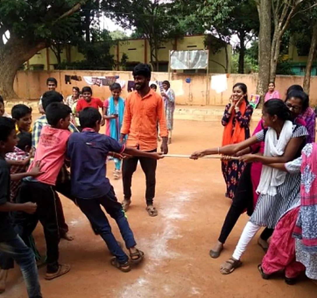 Children and young women facilitators playing tug-of-war in a school ground during a Tackle session